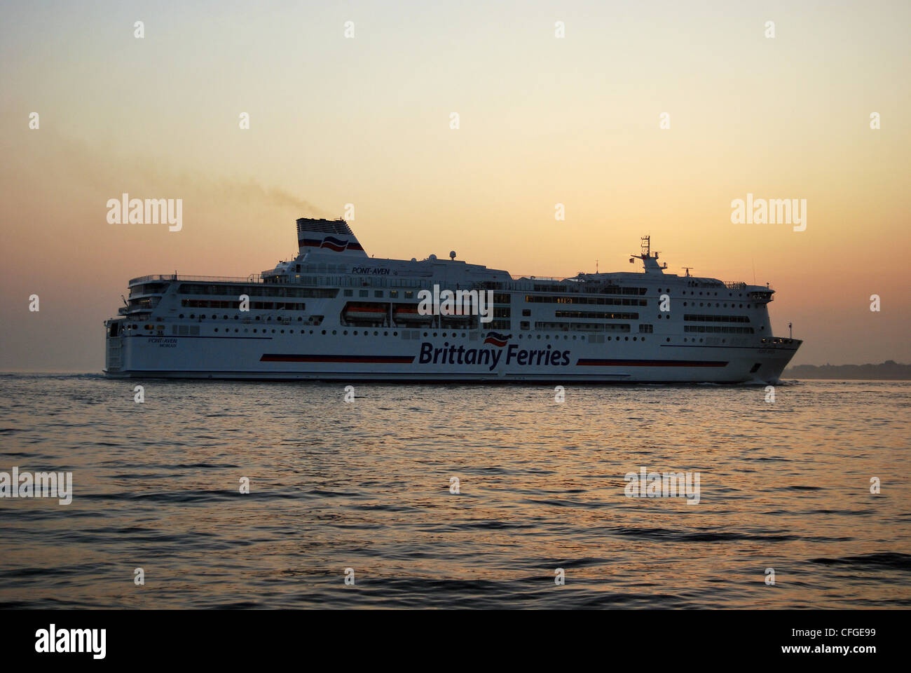 Un canale trasversale traghetto arriva a Portsmouth a seguito di una barca a vela dalla Francia al tramonto. Foto Stock