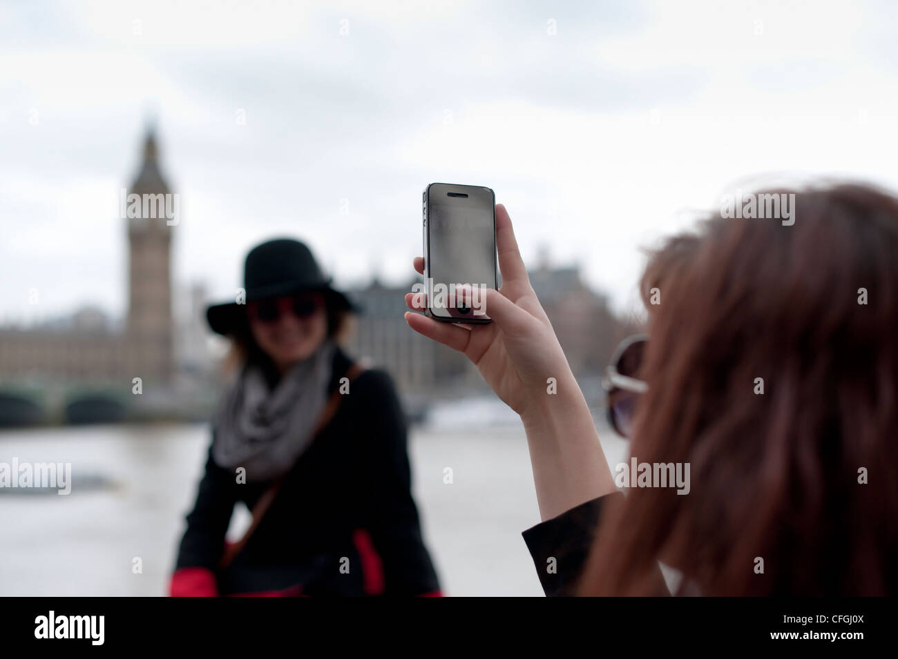 I turisti nella Southbank Londra per scattare delle foto con un iphone con il Palazzo di Westminster in background Foto Stock