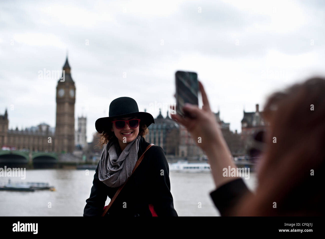 I turisti nella Southbank Londra per scattare delle foto con un iphone con il Palazzo di Westminster in background Foto Stock