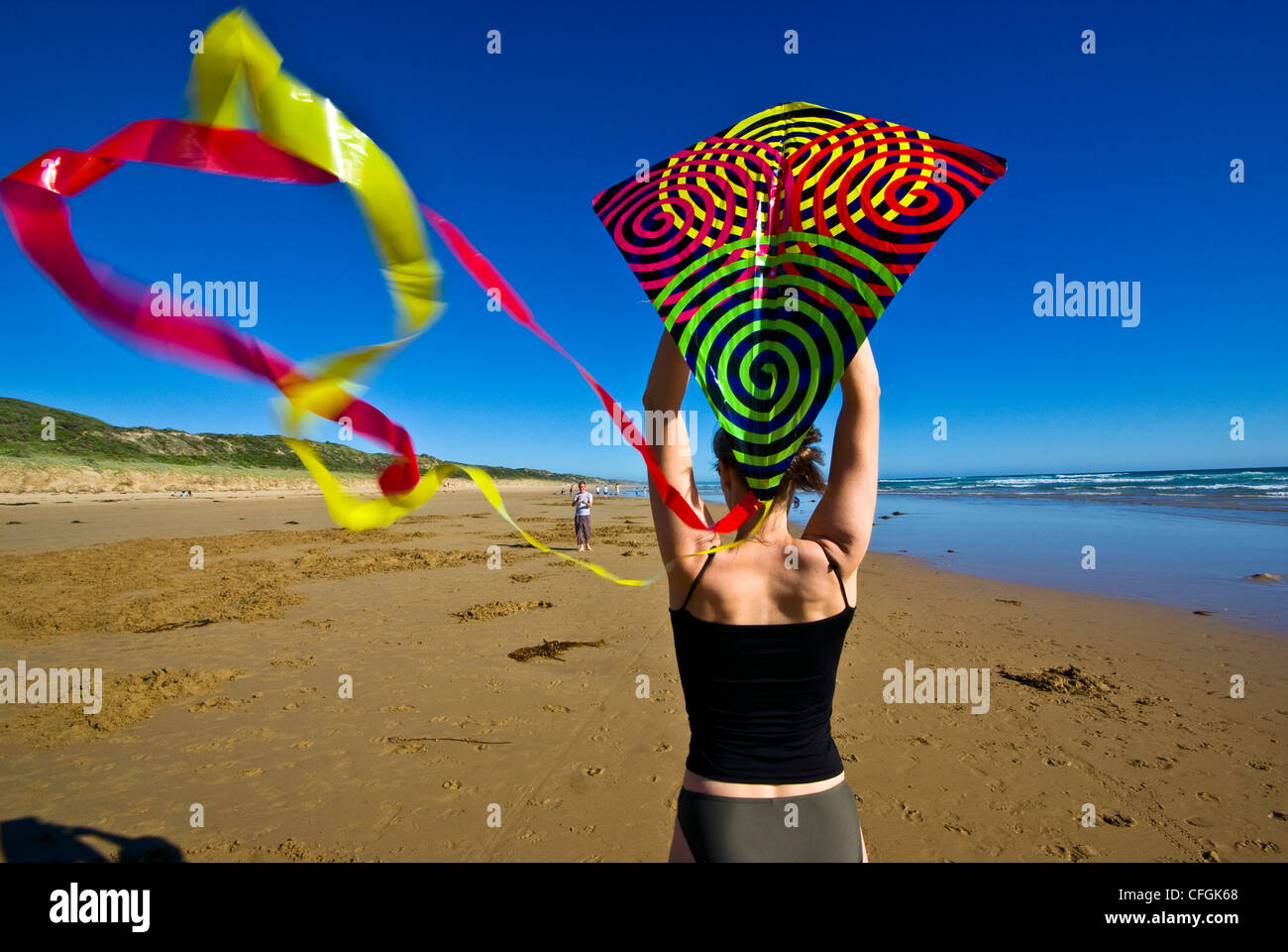 Una donna si prepara a lanciare un aquilone su una spiaggia spazzate dal vento durante l'estate. Foto Stock