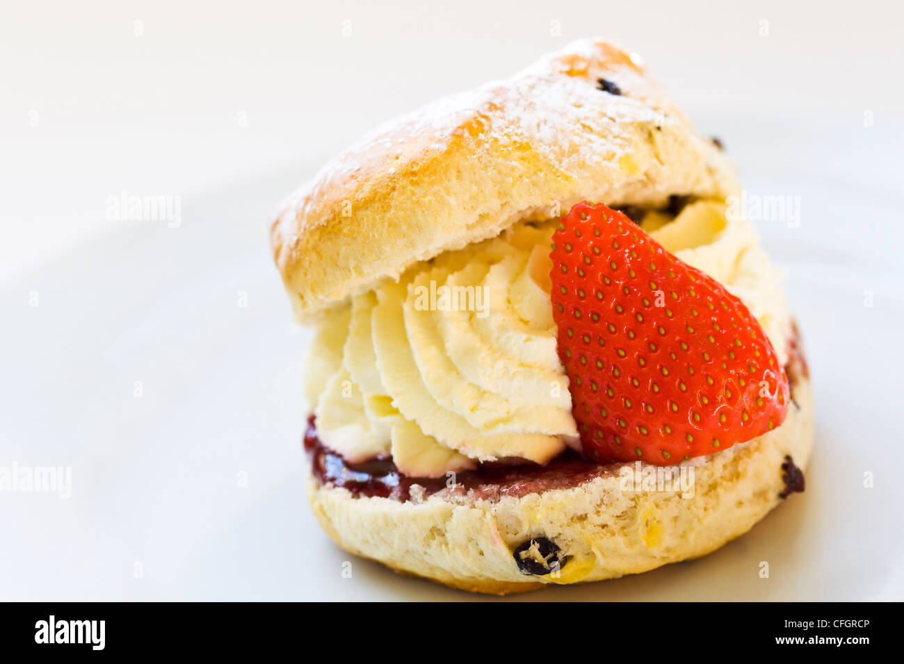 Un Scone riempiti con panna fresca e fragole Foto Stock