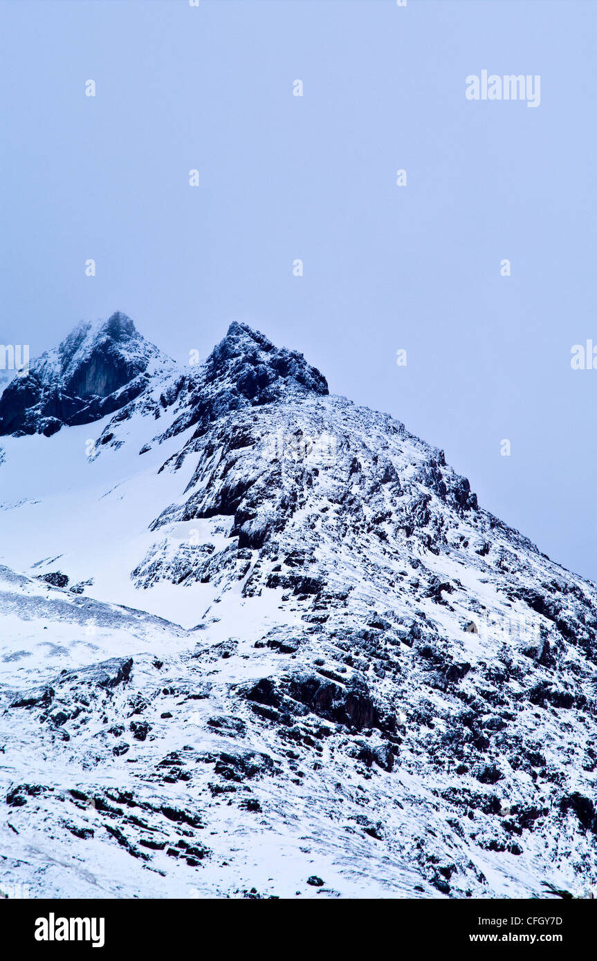Un ambiente inospitale picco di montagna in una bufera di neve coperta di neve e ghiaccio. Foto Stock