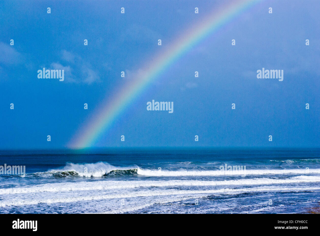 Un iridato arcobaleno tocca l'oceano e onde enormi a Bells Beach. Foto Stock