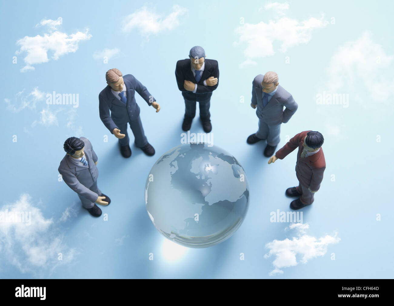 Gli imprenditori in miniatura che circonda globo di vetro Foto Stock