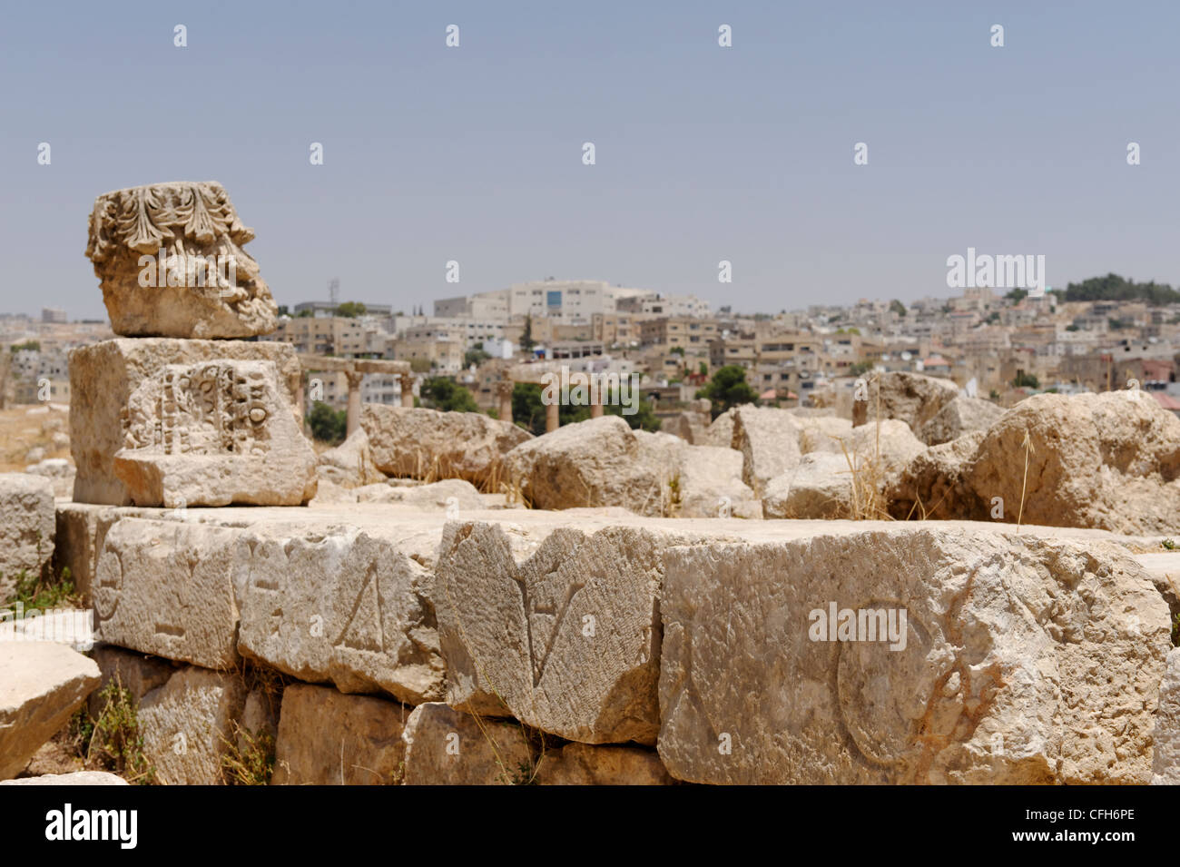 Jerash. La Giordania. Vista del greco antico di scritte inscritto muro di pietra a la città antica. In fondo è la città moderna Foto Stock