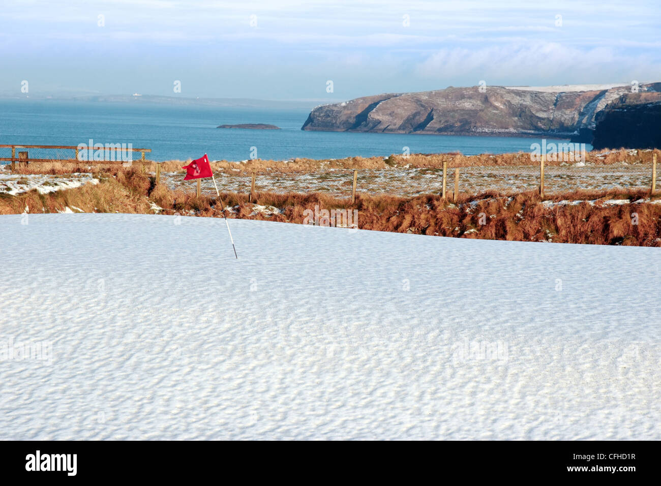 Copertura di neve su un campo da golf in irlanda in inverno con il mare e le scogliere in background Foto Stock