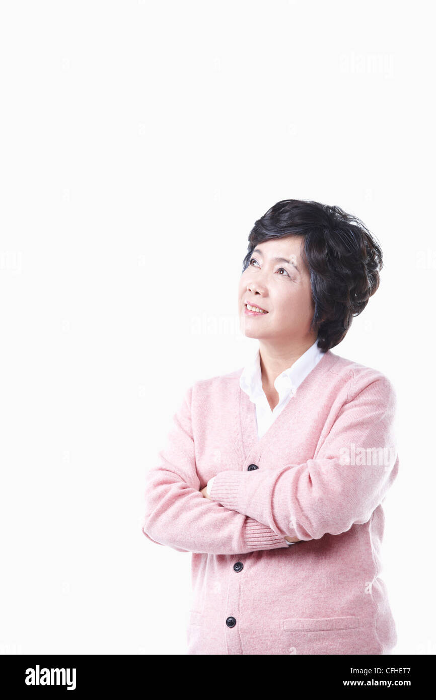 Una donna anziana guardando il cielo con le braccia piegate Foto Stock