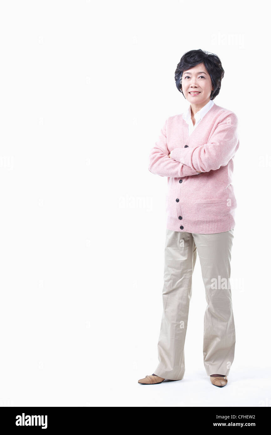 In piedi di una donna anziana con le braccia piegate Foto Stock