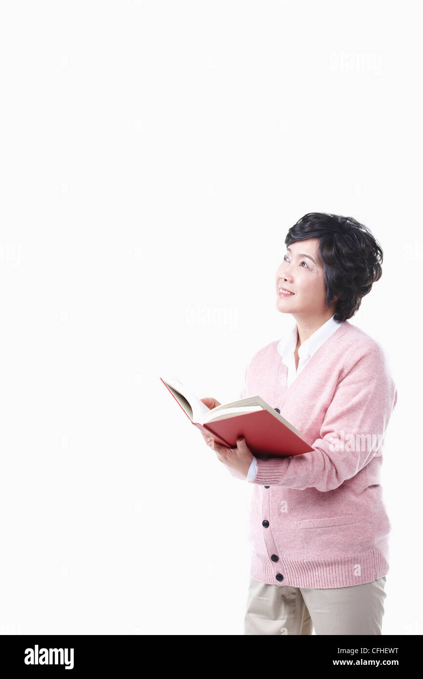 Una donna anziana guardando il cielo con un libro Foto Stock