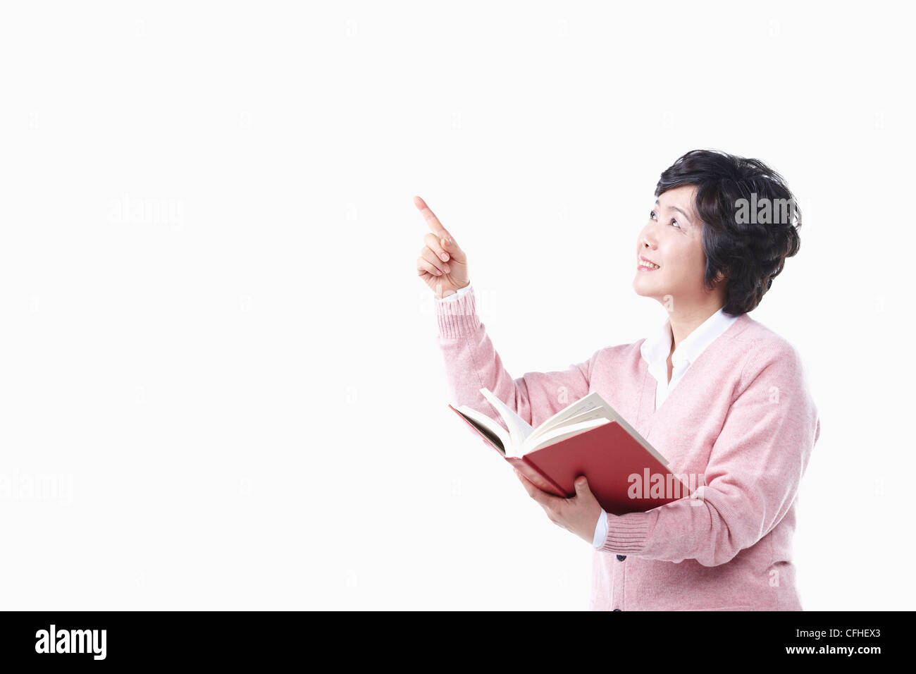 Una donna anziana rivolta verso l'aria con un libro Foto Stock