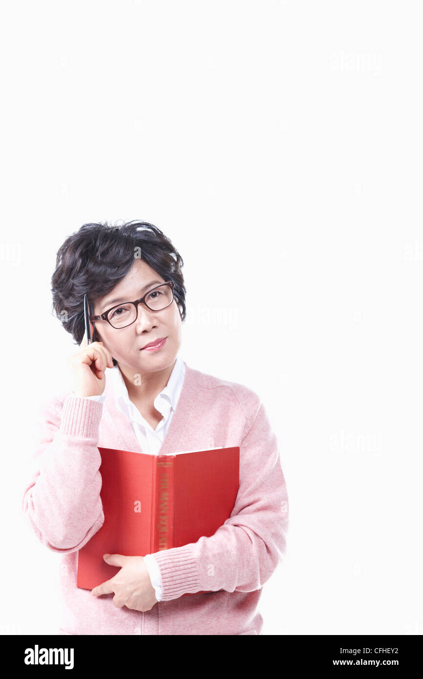 Il pensiero di una donna anziana con un libro e penna Foto Stock
