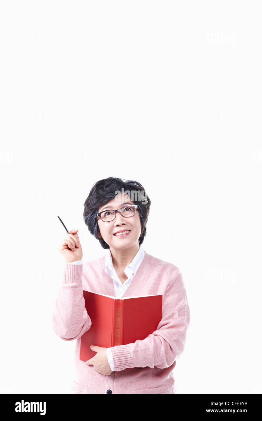 Il pensiero di una donna anziana con un libro e penna Foto Stock