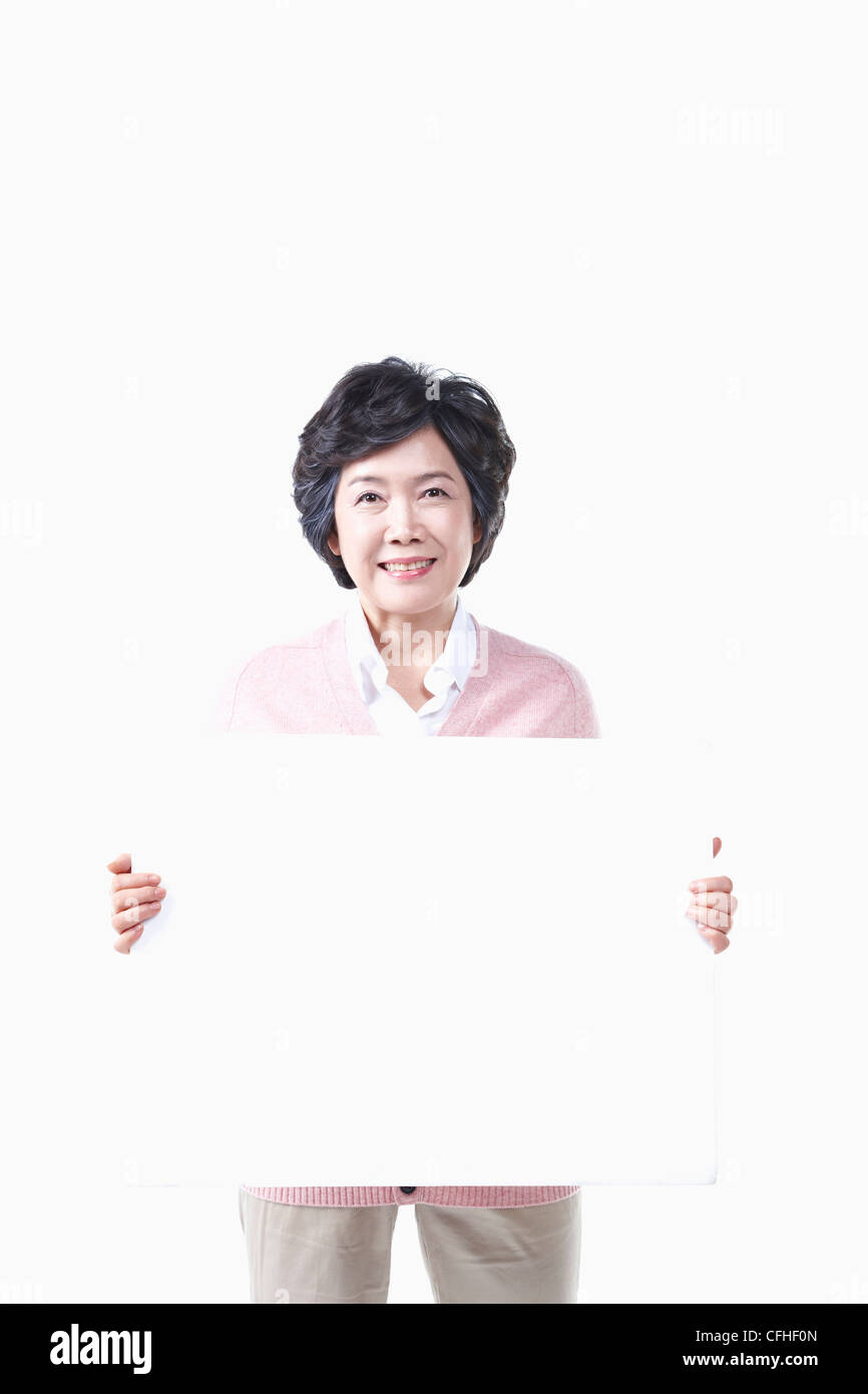 Una donna anziana con un pannello bianco Foto Stock