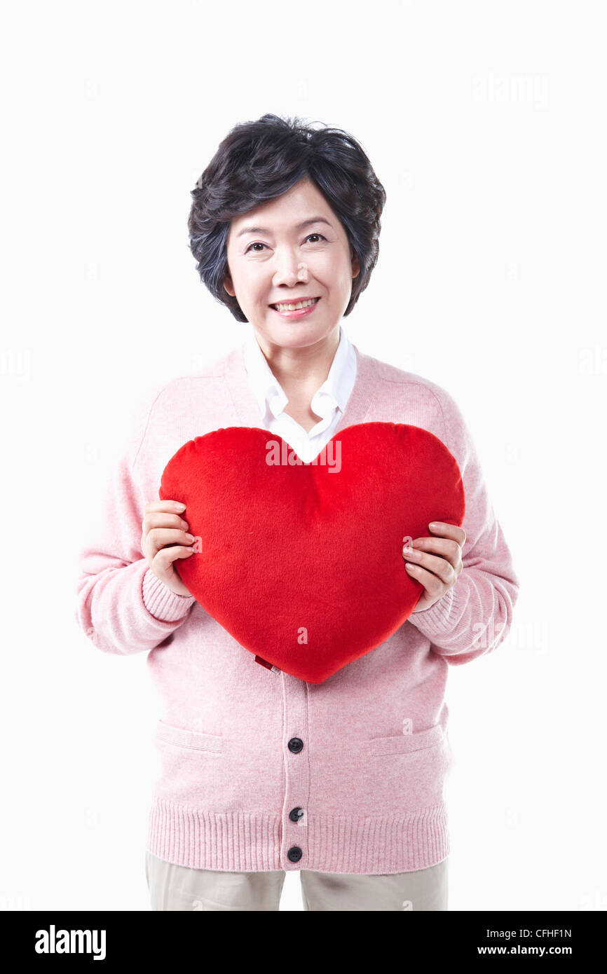 Una donna anziana con il cuore rosso Foto Stock
