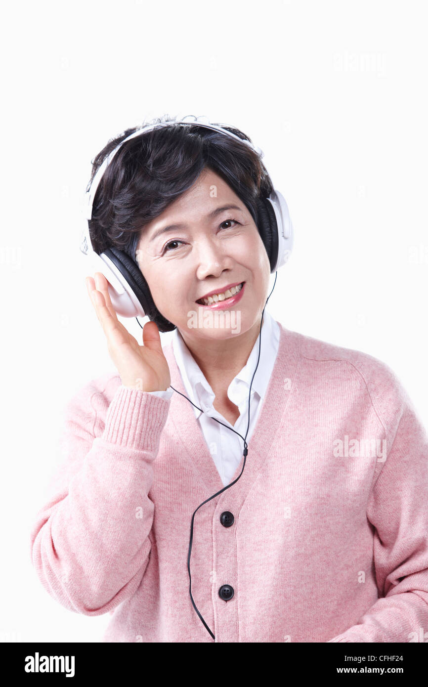 Una donna anziana l'ascolto di musica con un auricolare Foto Stock