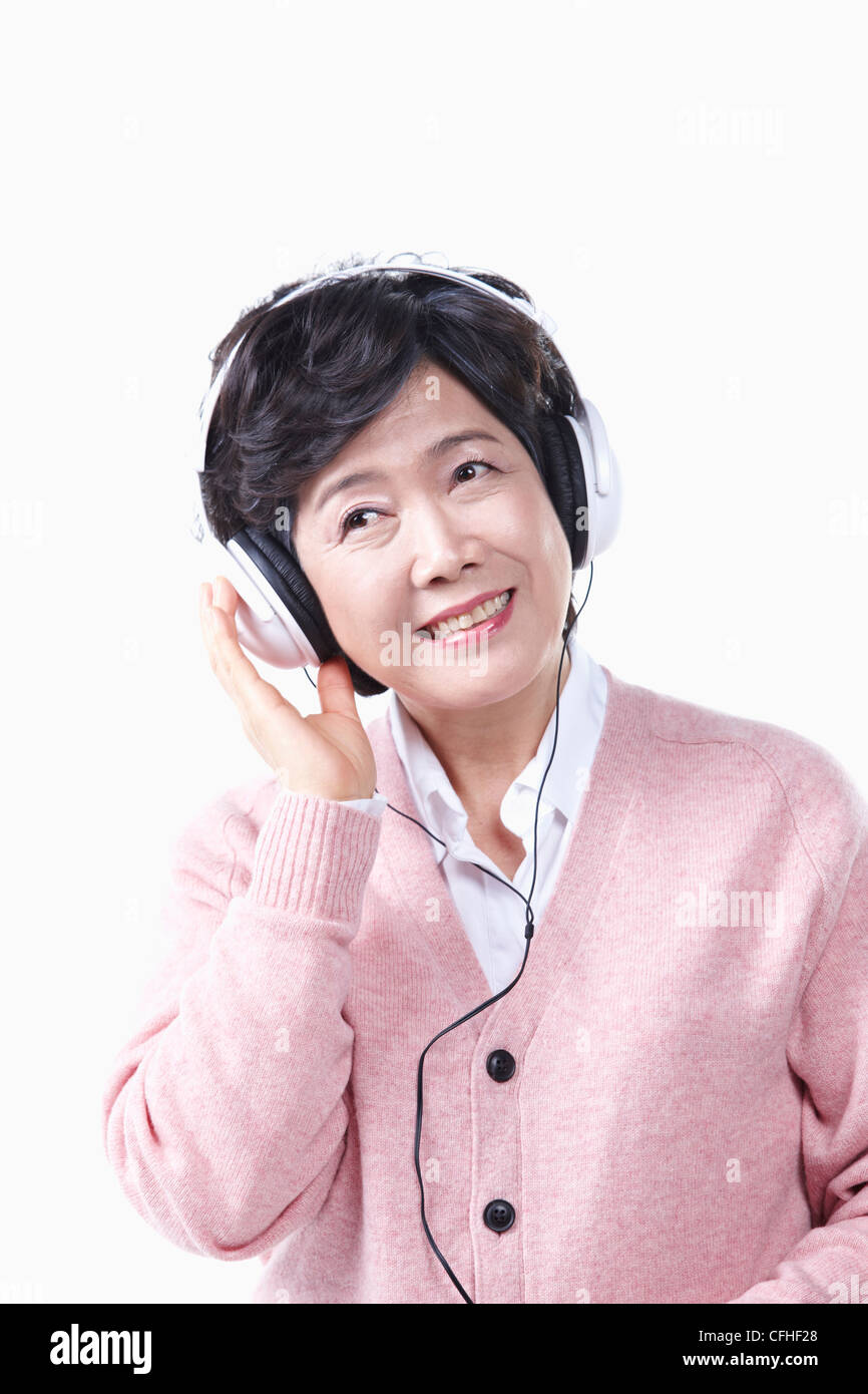 Una donna anziana l'ascolto di musica con un auricolare Foto Stock