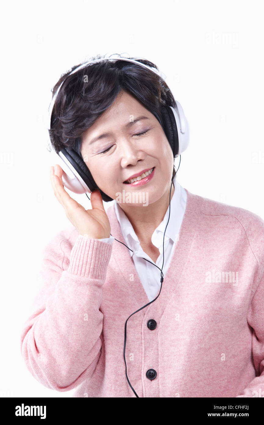 Una donna anziana l'ascolto di musica con un auricolare Foto Stock