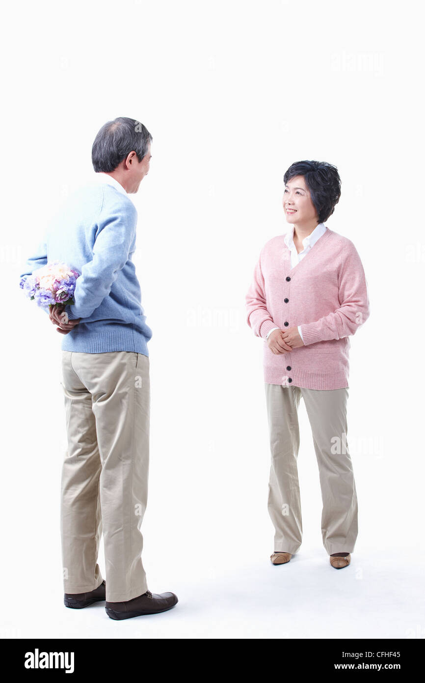 Un uomo anziano come nascondere un mazzo di fiori per una donna anziana Foto Stock