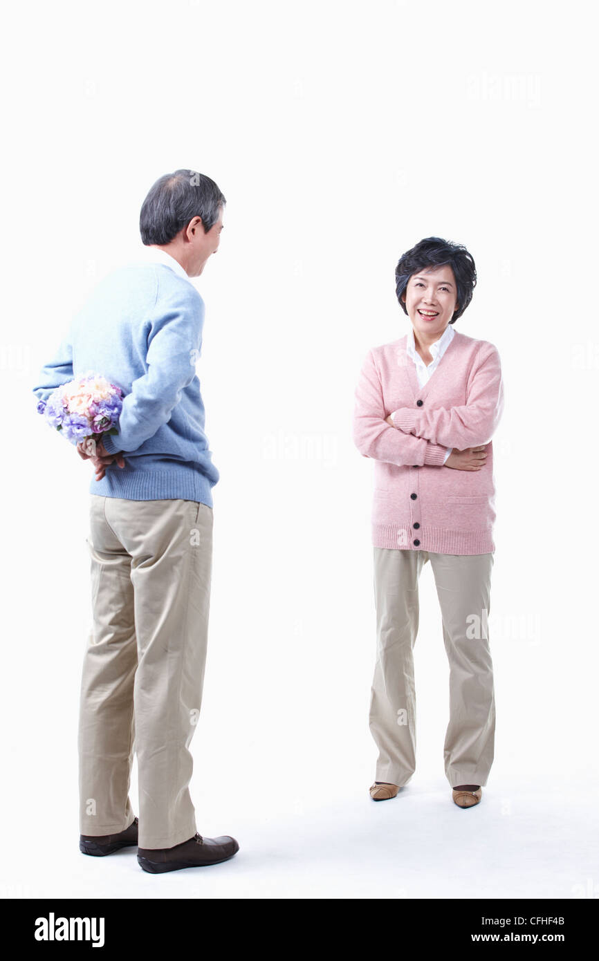 Un uomo anziano come nascondere un mazzo di fiori per una donna anziana Foto Stock