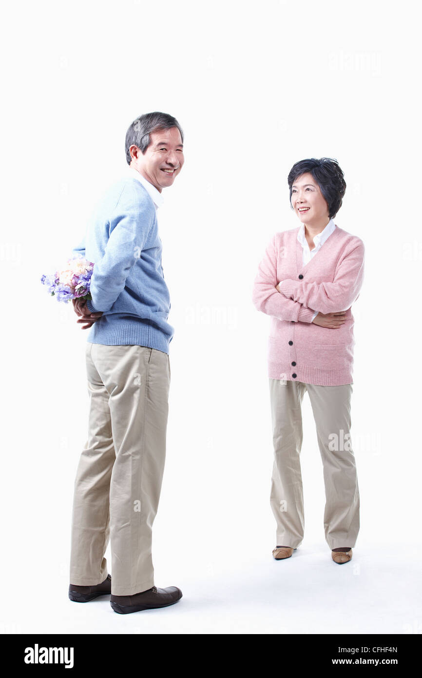 Un uomo anziano come nascondere un mazzo di fiori per una donna anziana Foto Stock