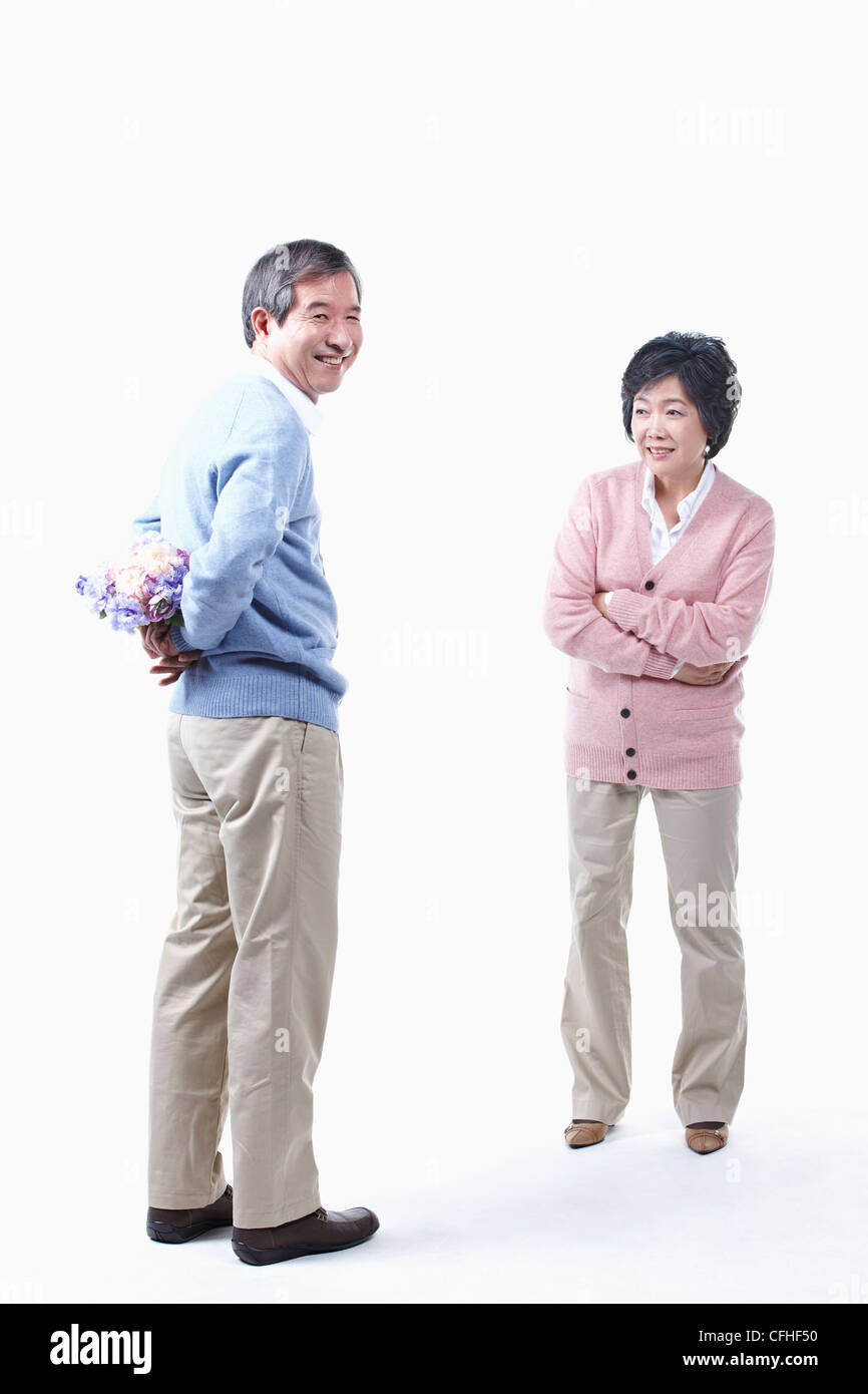 Un uomo anziano come nascondere un mazzo di fiori per una donna anziana Foto Stock