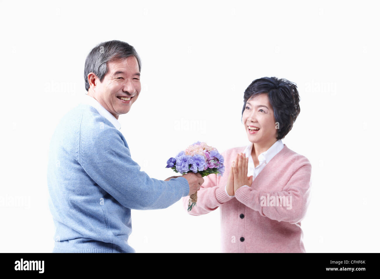 Un uomo anziano dando un mazzo di fiori per una donna anziana Foto Stock
