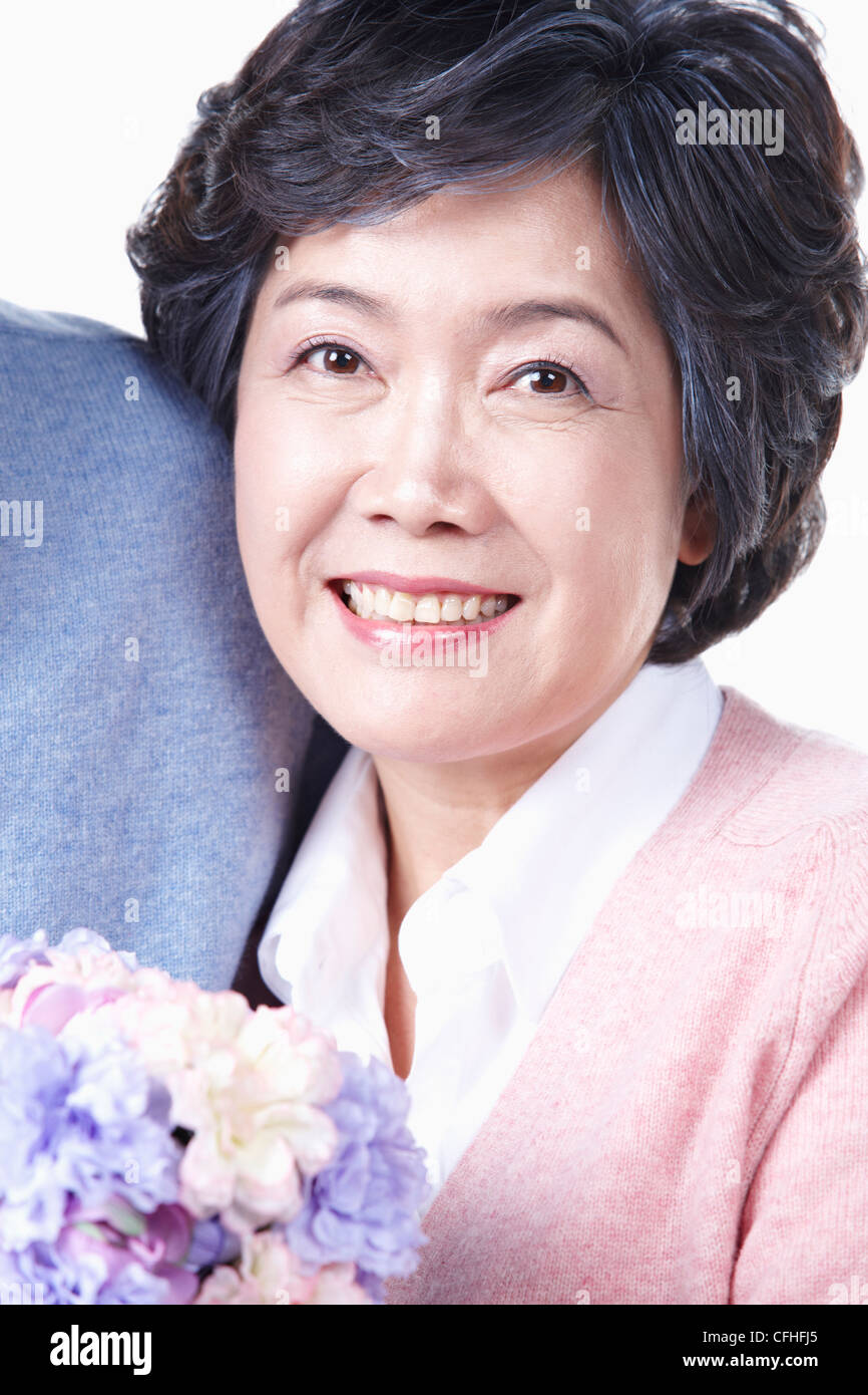 Un sorridente donna anziana con un mazzo di fiori Foto Stock