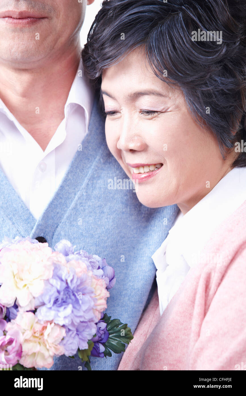 Una donna anziana con un uomo anziano e un mazzo di fiori Foto Stock