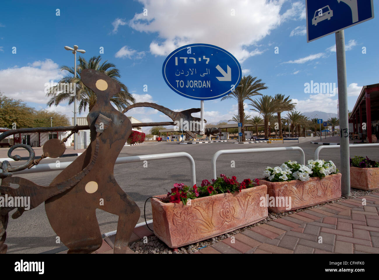 Whimsical di scultura con il blu e il cartello bianco che indica l'Israel-Jordan Wadi Araba Crossing/confine meridionale Foto Stock