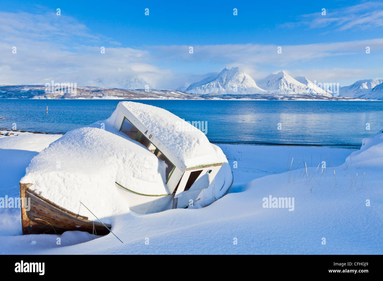 Piccola coperta di neve barca al molo Breivikeidet guardando attraverso Ullsfjord, verso il sud delle Alpi Lyngen, Troms, Norvegia, Europa Foto Stock