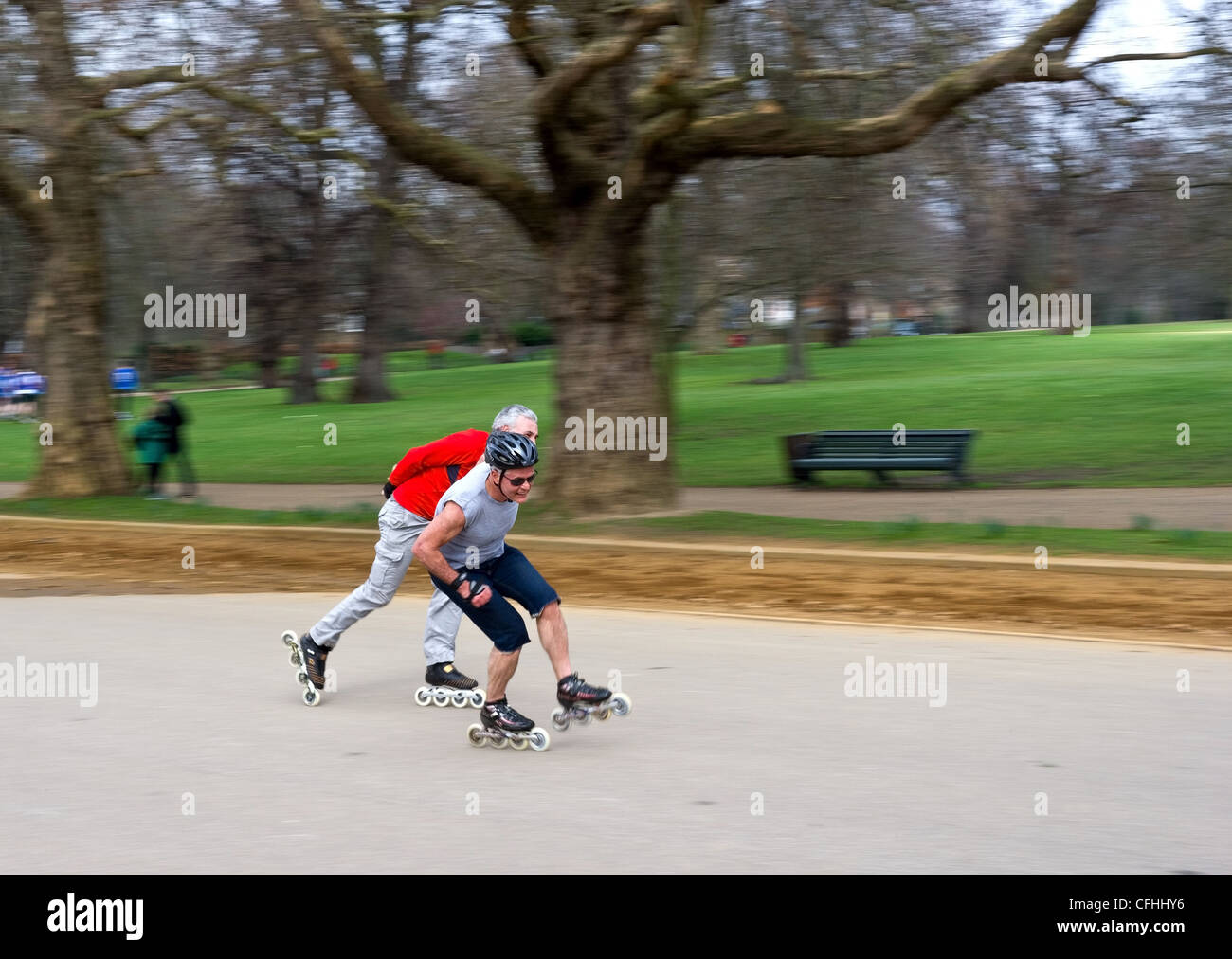 Due uomini pattinaggio in velocità attraverso Hyde Park di Londra Foto Stock