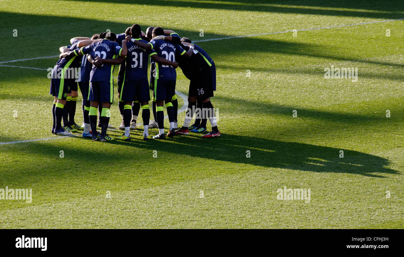 Wigan Athletic Football giocatori in un huddle prima di kick off con una lunga ombra Foto Stock