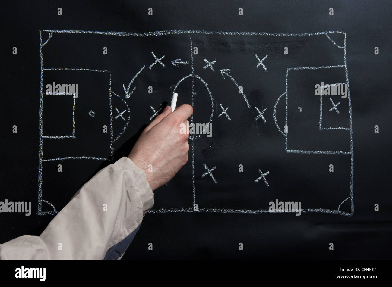 L'uomo il disegno di una partita di calcio di tattica e strategia con il bianco gesso su una lavagna. Foto Stock