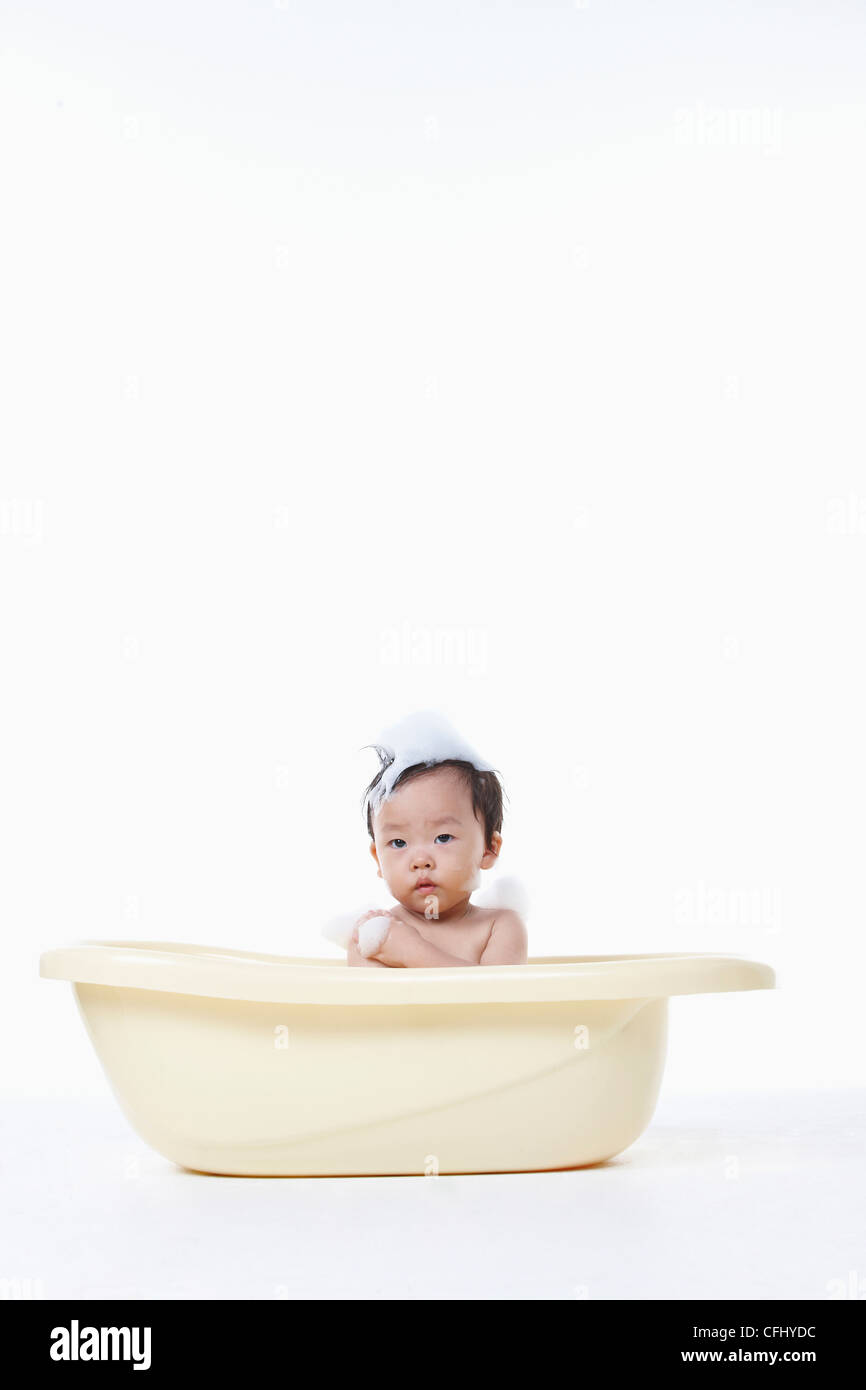 Un bambino di prendere un bagno nella vasca con la bolla sul suo corpo Foto Stock