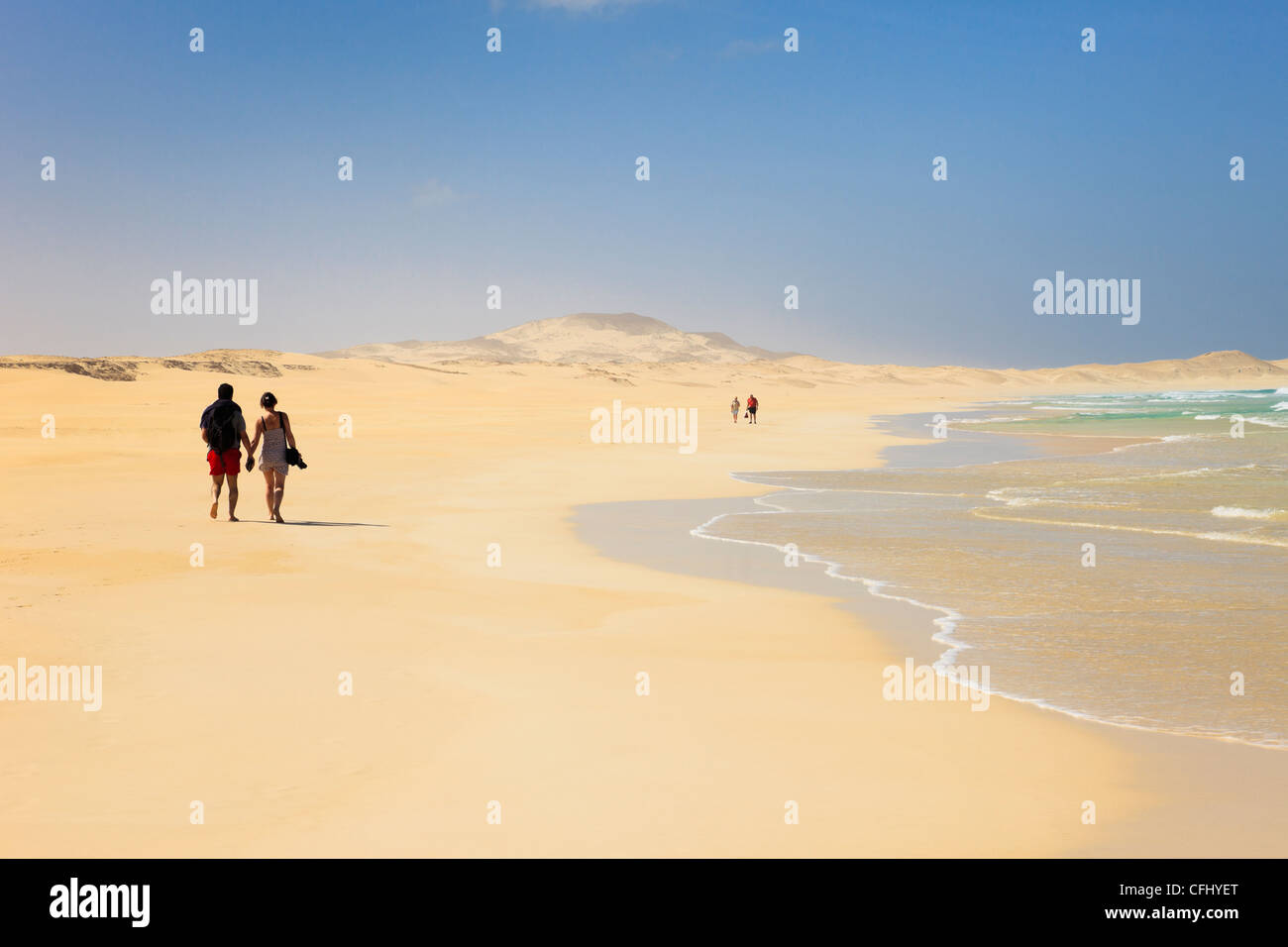 Le coppie passeggiando lungo la riva del tranquillo lunga spiaggia di sabbia bianca di Praia de Chaves, Rabil, Boa Vista, Isole di Capo Verde, Africa. Foto Stock