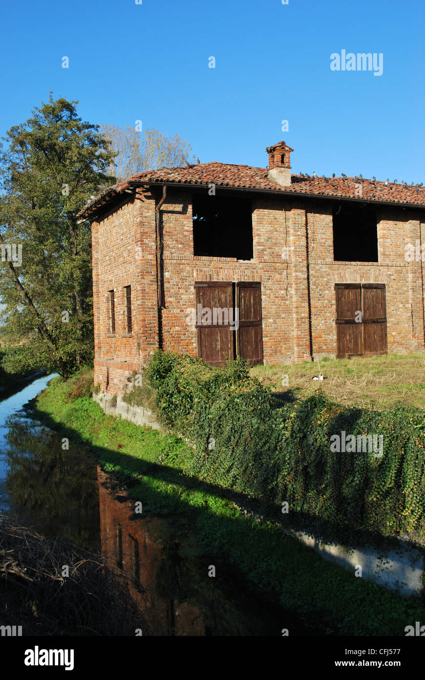 Vecchio abbandonato county house su un canale in una giornata di sole, Italia Foto Stock