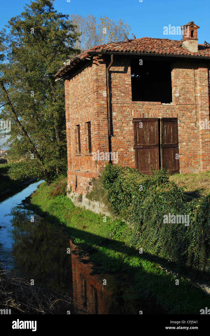 Vecchio abbandonato county house su un canale in una giornata di sole, Italia Foto Stock