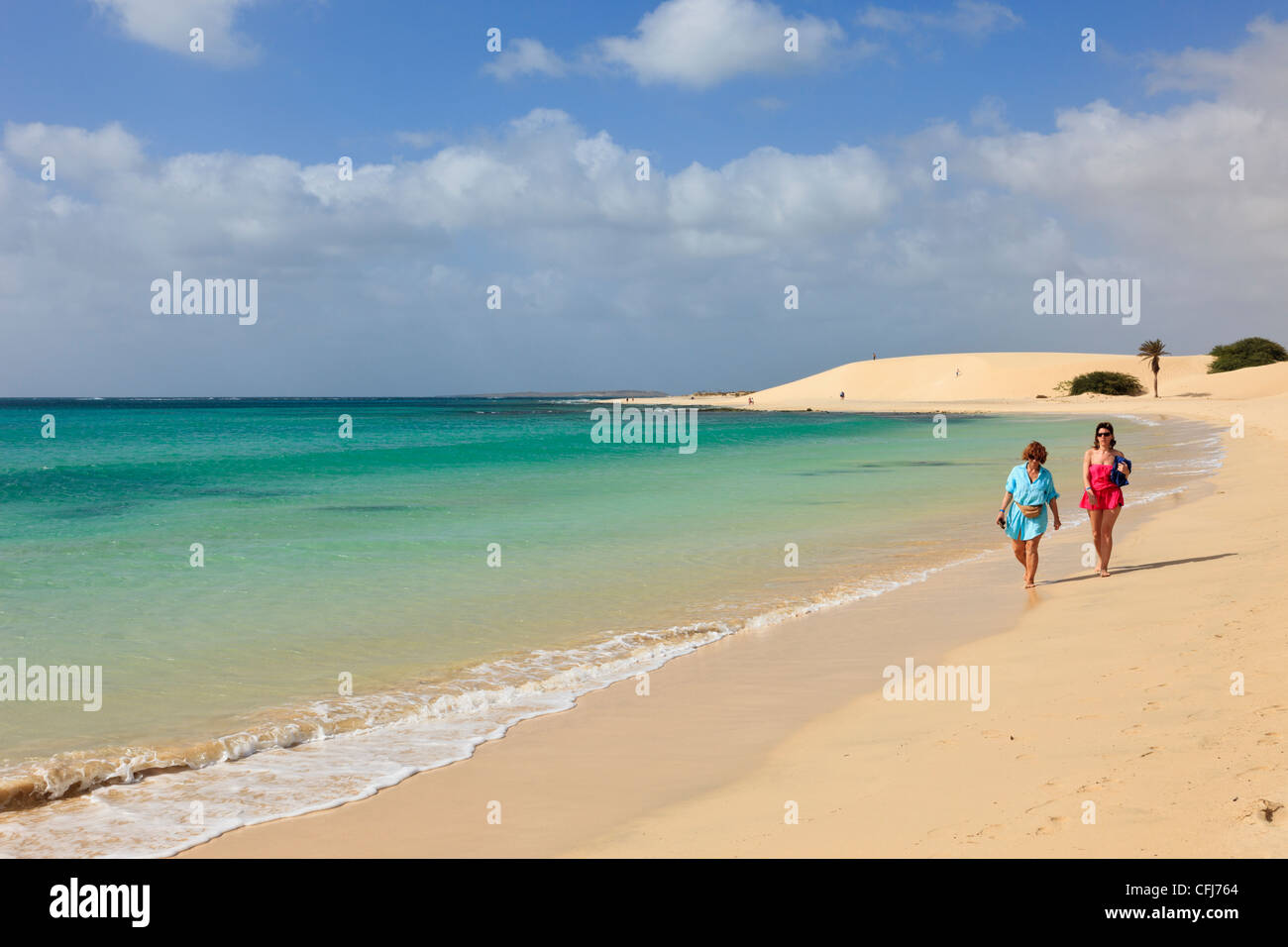 Praia de Chaves, Boa Vista, Isole di Capo Verde. Due donne camminando lungo la riva del mare della tranquilla spiaggia di sabbia bianca accanto al mare turchese Foto Stock