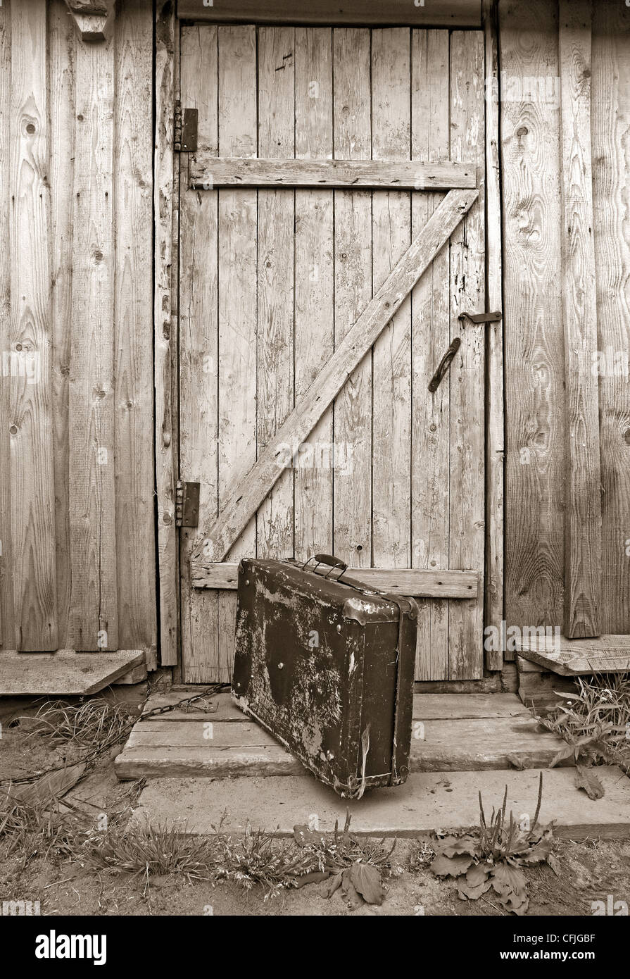 Vecchio valise vicino alla porta di legno, seppia Foto Stock