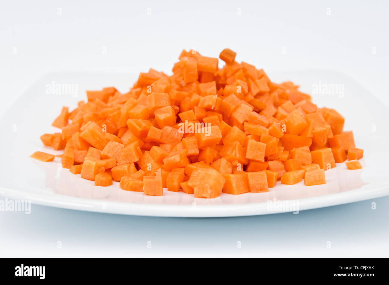Studio shot di carote tagliate a dadini in piastra bianca contro uno sfondo bianco Foto Stock