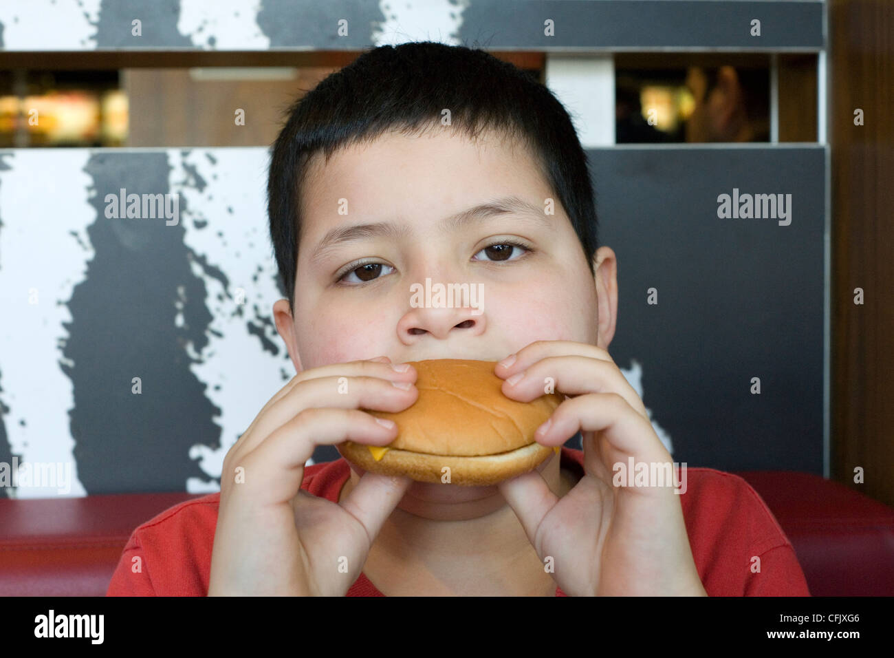 Ragazzo giovane godendo di un hamburger in macdonalds Foto Stock