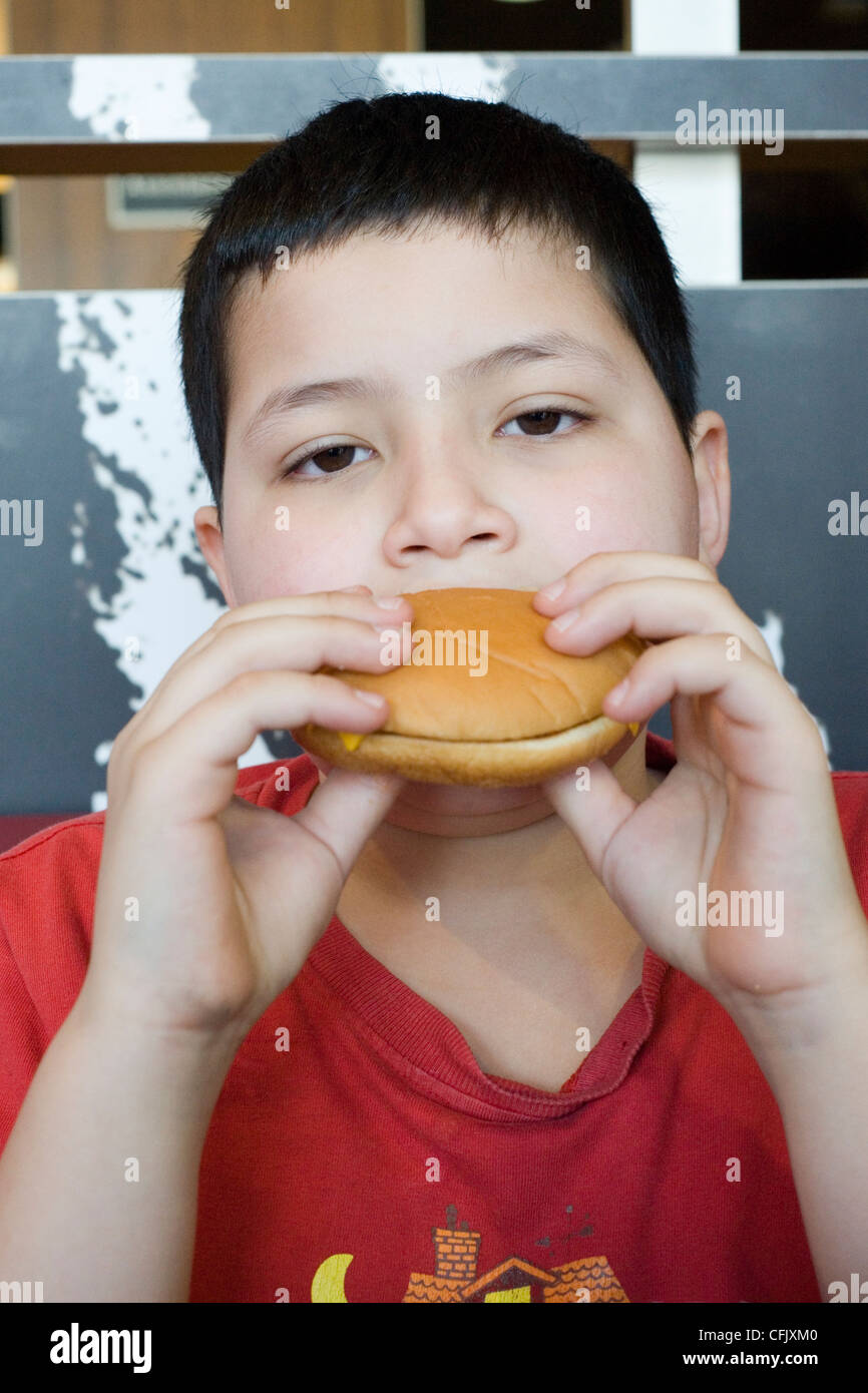 Ragazzo giovane godendo di un hamburger in macdonalds Foto Stock
