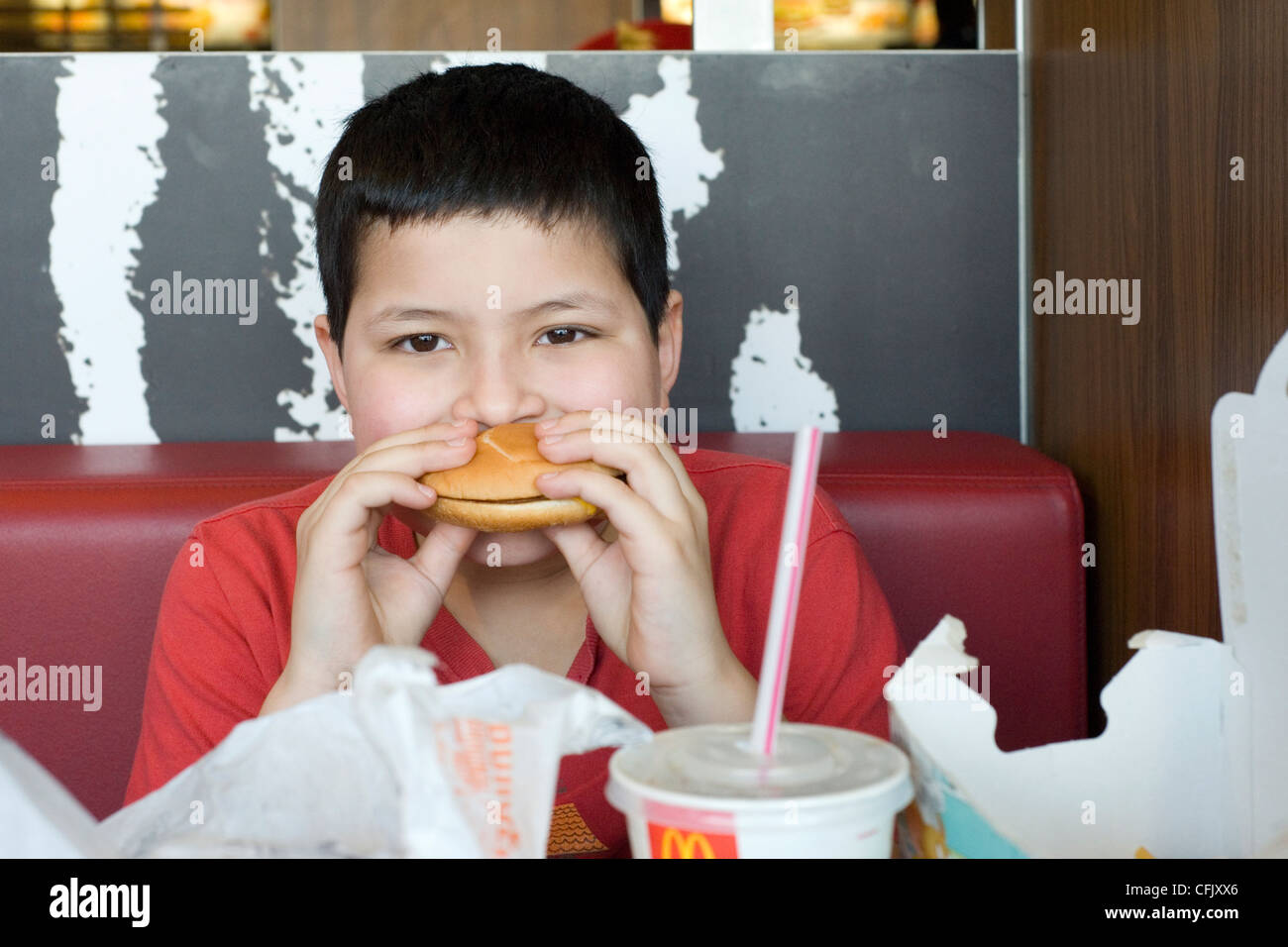 Ragazzo giovane godendo di un hamburger in macdonalds Foto Stock