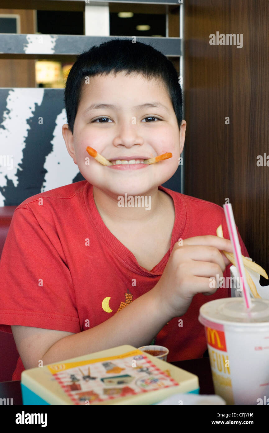 Ragazzo giovane godendo di un hamburger in macdonalds Foto Stock