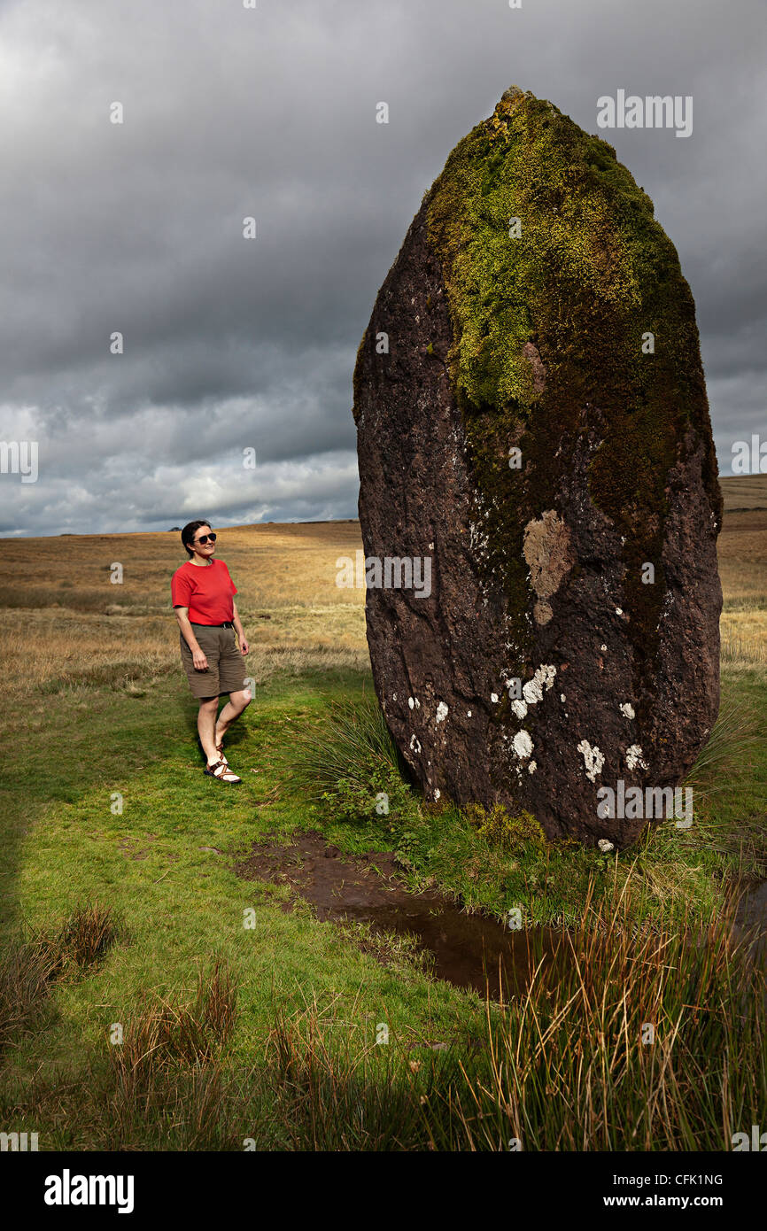 Persona in piedi accanto a Maen Llúria pietra permanente, Parco Nazionale di Brecon Beacons, Powys, Wales, Regno Unito Foto Stock