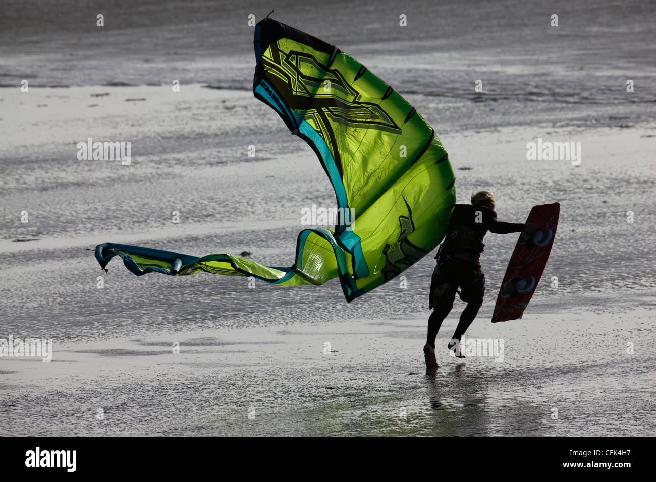 Kite surfer lotte contro il vento sulla spiaggia di Newgale Sands, Pembrokeshire, Galles Foto Stock