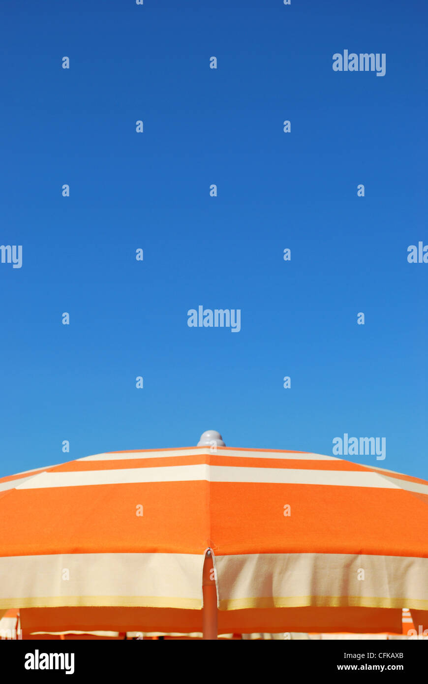 Arancio listati ombrellone oltre il cielo blu, libera lo spazio per testo, Rimini, Italia Foto Stock