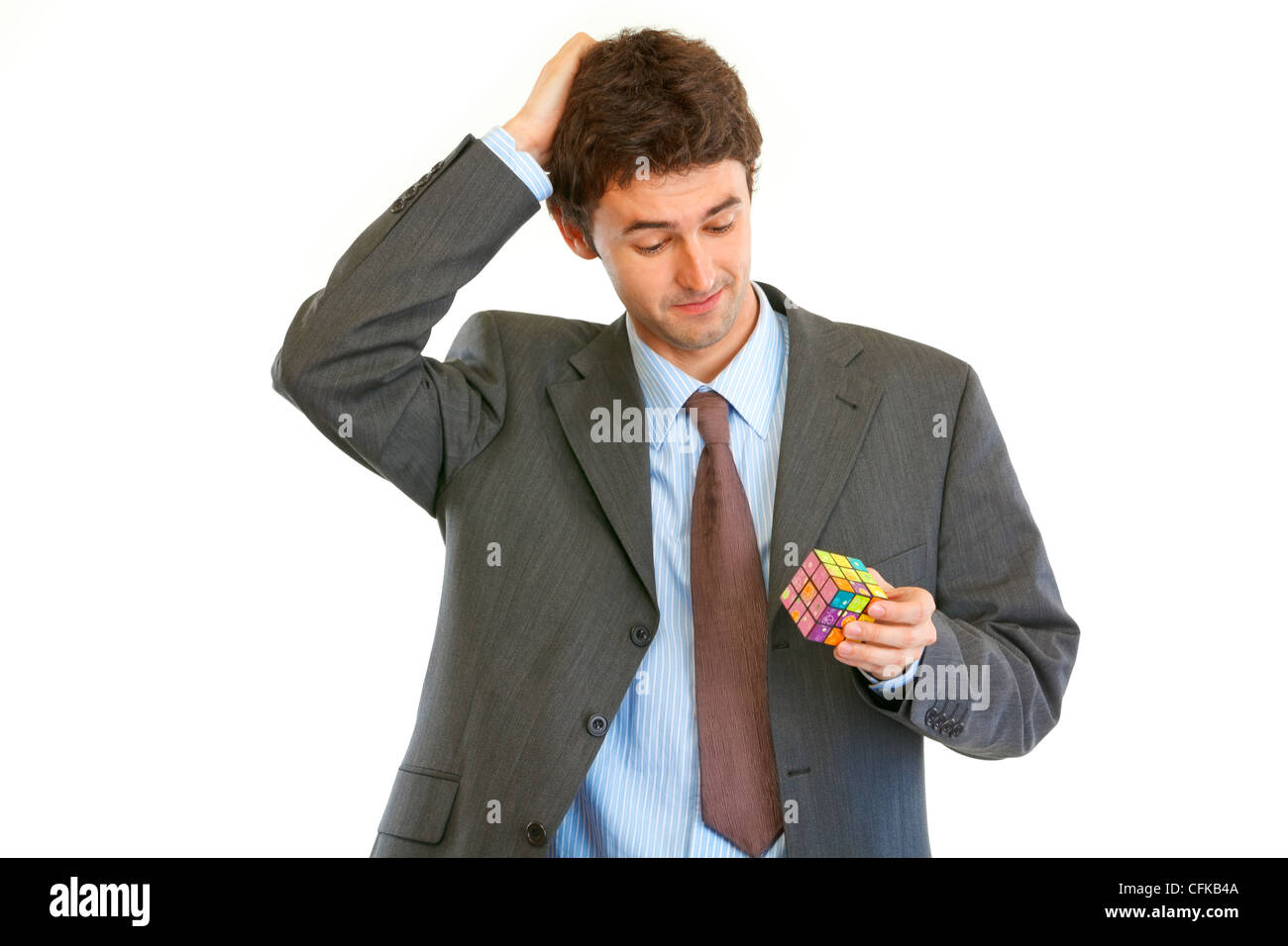 Imprenditore confuso tenendo il cubo di Rubik in mano isolato su bianco Foto Stock