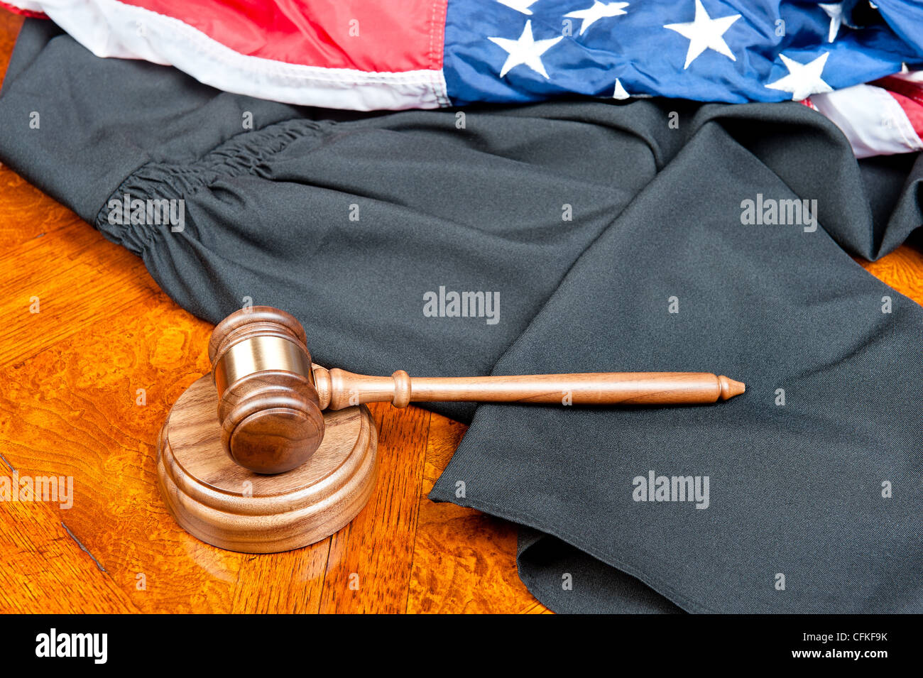 Un giudice di camice e martello con blocco audio su un profondo e ricco di legno colorato e desktop bandiera americana Foto Stock