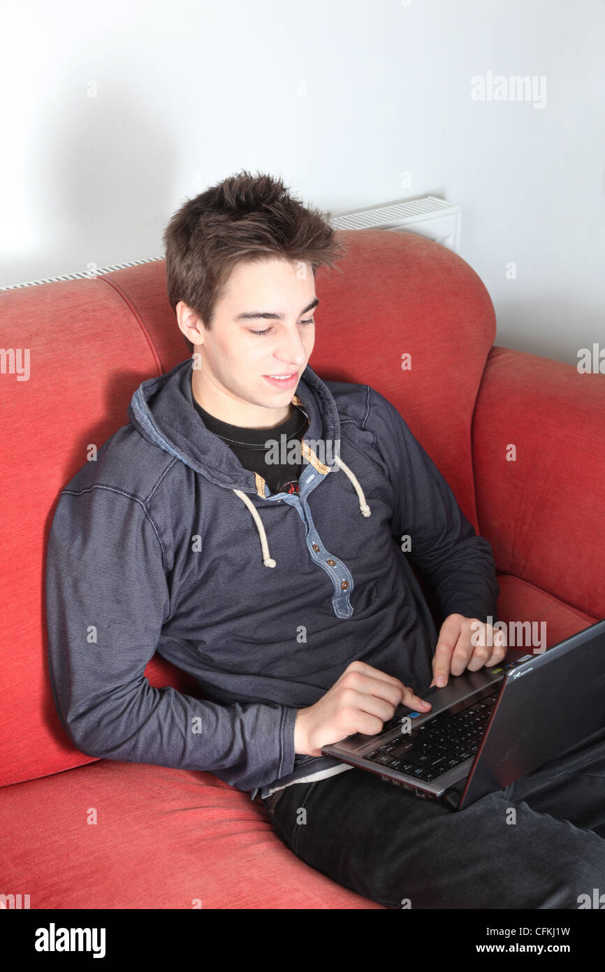 Giovane maschio seduto da solo utilizzando un computer portatile. Foto Stock